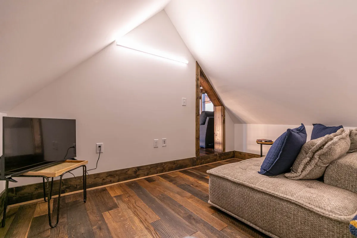 This image features a comfortable sofa positioned in front of a television, set on warm wooden flooring. The space is inviting, ideal for group gatherings, movie nights, or casual relaxation. The overall mood is inviting and perfect for unwinding after a day of adventure.